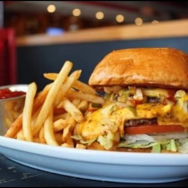 Cheeseburger with melted cheese, lettuce, tomato, and onion, served with a side of fries and ketchup.